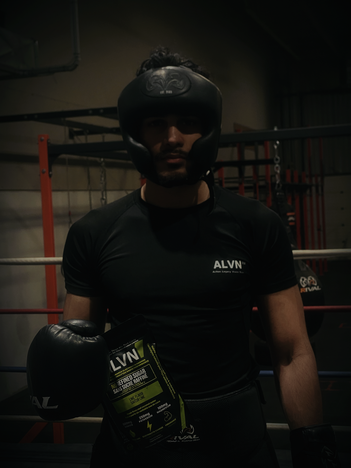 Person wearing a black helmet and holding a green bag with 'ALVN' branding in a dark indoor setting.
